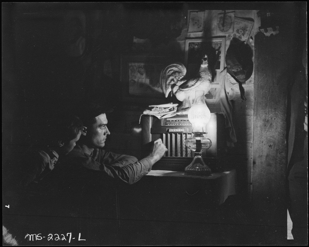 Charlie_Lingar_and_his_son_listen_to_their_battery_radio._He_has_worked_for_the_company_for_fourteen_years_but_was..._-_NARA_-_541193